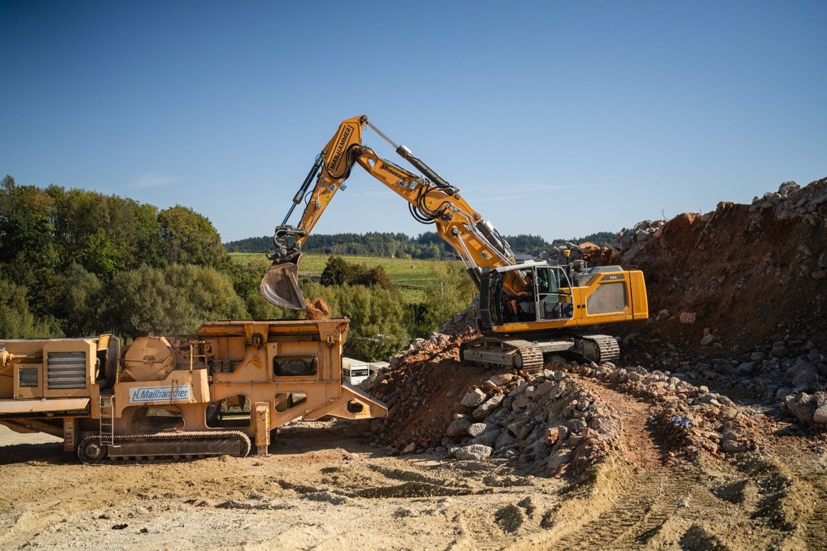 Kettenbagger belädt einen Brecher auf der Baustelle